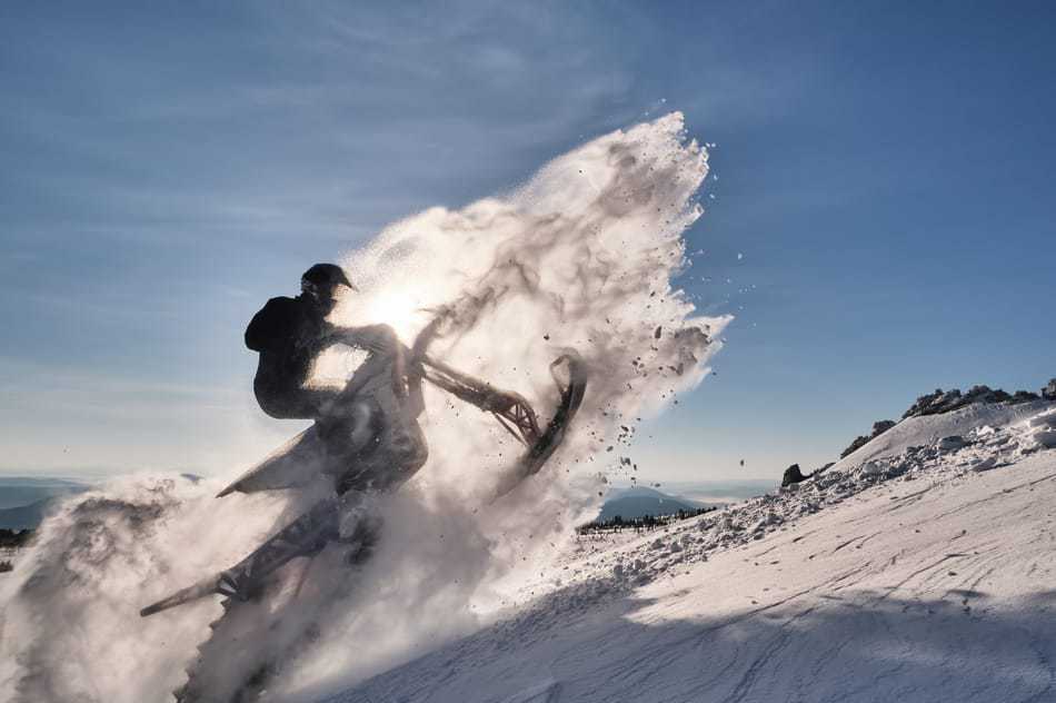 A dirt bike converted to a snow bike ripping through the snow.